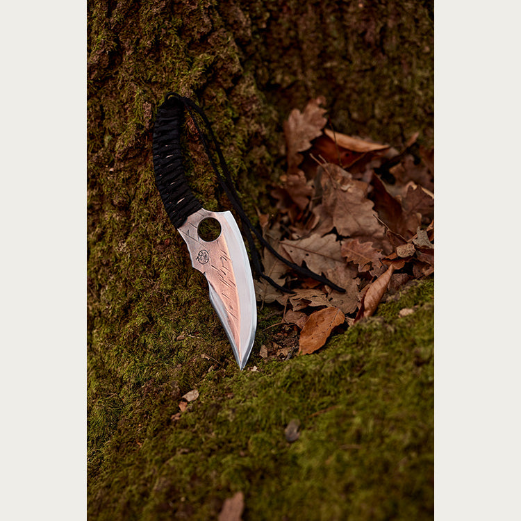 Almazan Kitchen Predator Nož naslonjen na drvo prekriveno mahovinom. 
