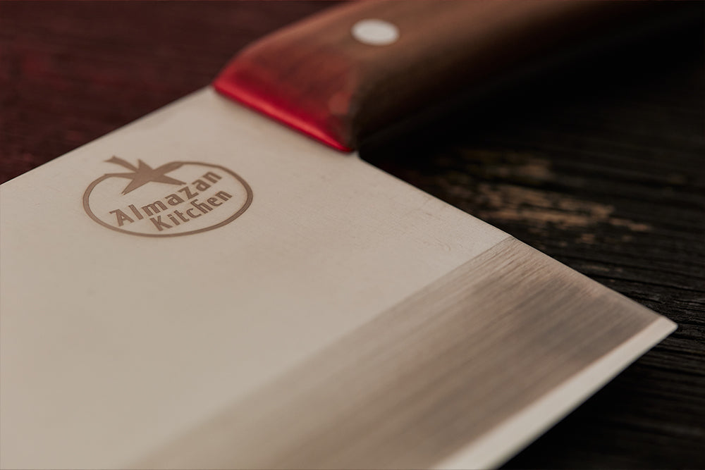 Almazan Kitchen logo u fokusu na oštrici noža. 